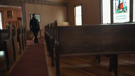 Pastor-in-black-suit-walking-in-church-sitting-in-pew-in-cinematic-slow-motion