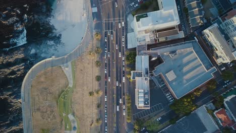 Vista-De-Arriba-Hacia-Abajo-De-Drones-Siguiendo-Los-Autos-En-La-Carretera-Durante-La-Puesta-De-Sol-En-Ciudad-Del-Cabo,-Sudáfrica