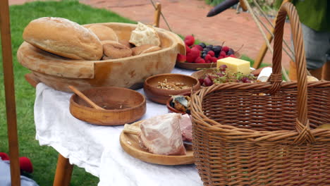 Artisanal-bread-and-cheese-with-meat-on-a-wooden-platter-with-fresh-fruit,-evokes-a-rustic-medieval-feast-or-viking-picnic