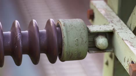Close-up-of-a-weathered-ceramic-insulator-on-a-power-line,-detail-rich-texture-visible