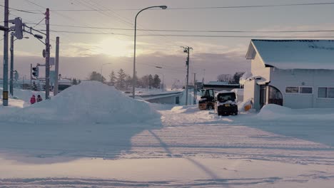 Tractor-Dumping-Snow-Into-Pile-Beside-Snow-Covered-Road-In-Omu-Hokkaido-During-Sunset