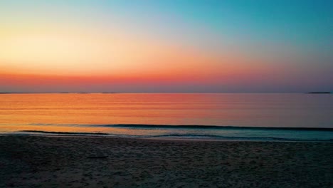 Colorful-Beach-Sunset-in-Saco,-Maine-with-Bright-Colors-Reflecting-off-Calm-Rippling-Ocean-Waves-Along-the-New-England-Atlantic-Coastline