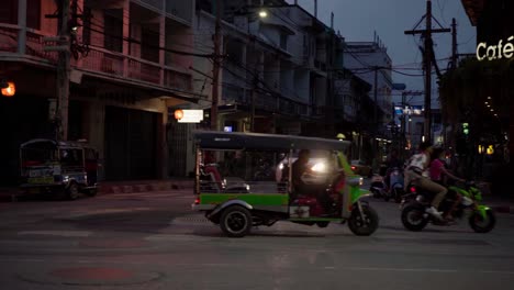 Un-Modo-Extranjero-De-Transporte-En-Taxi,-Un-Tuk-Tuk-Verde-Brillante,-Viaja-Por-Una-Calle-De-Una-Ciudad-En-Tailandia-Por-La-Noche