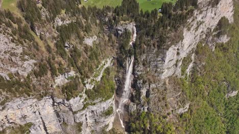 Ein-Spektakulärer-Wasserfall,-Der-Durch-Schroffe-Klippen-In-Einem-üppig-Grünen-Tal-Stürzt,-Aufgenommen-Während-Des-Tages,-Luftaufnahme