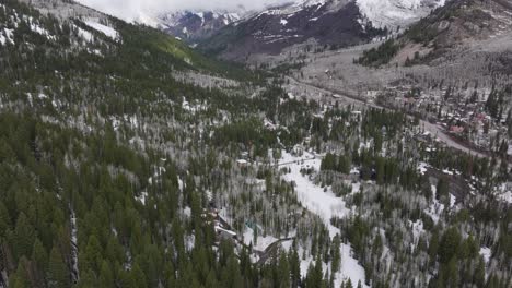 Aerial-push-in-wide-view-of-mountains-and-forest-near-Solitude-Resort-in-Big-Cottonwood-Canyon,-Utah-during-late-spring