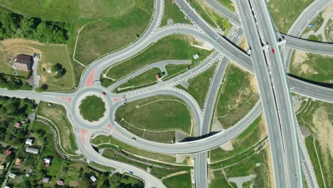 Aerial-drone-zoom-in-footage-captures-intricate-highway-junction-with-cars-navigating-complex-roundabouts-and-intersecting-roads