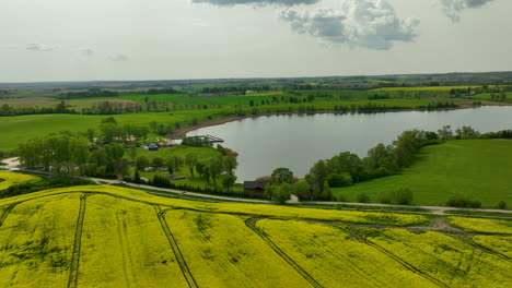 A-wide-view-of-a-countryside-landscape-featuring-a-large-lake-surrounded-by-green-fields-and-trees