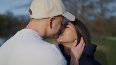 Lovely-couple-at-park,-guy-gently-touch-cheek-and-kiss-girlfriend-on-lips