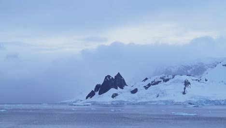 Sunset-Winter-Mountains-and-Ocean-in-Antarctica-with-Dramatic-Clouds-and-Sky,-Amazing-Scenery-on-Antarctic-Peninsula-Coast,-Sunset-Coastal-Scenery-in-Icy-Snowy-Scene-in-Cold-Weather