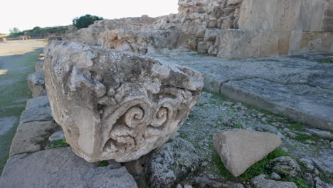 A-close-up-of-an-ornate-stone-fragment-at-the-Archaeological-Site-of-Nea-Paphos,-showing-detailed-carvings