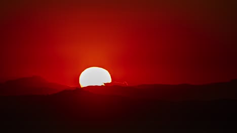 Luna-Llena-Levantándose-Contra-El-Horizonte-Rojo-Sobre-Las-Montañas