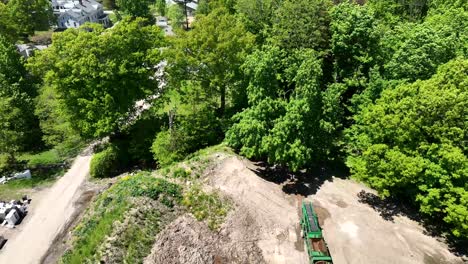 Drone-aerial-pullback-above-sediment-dirt-soil-stockpile-surrounded-by-trees