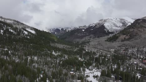 Aerial-pan-up-of-wide-snowy-mountain-range-near-Solitude-Resort-in-Big-Cottonwood-Canyon,-Utah-during-late-spring