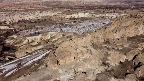 Cappadocia-Adventure:-Solo-Tourist-Hiker-Sits-Atop-Mountain-Cave-Dwelling-Enjoying-View-Towards-Göreme-Vast-Desert-Landscape-on-Horizon