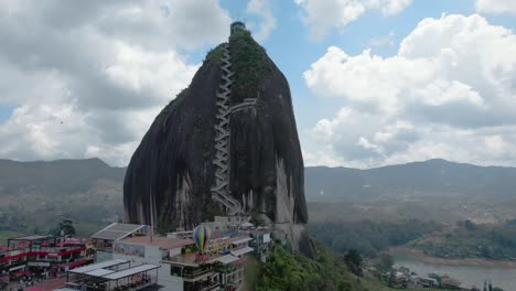 Aerial-shot-of-El-Peñón-de-Guatapé,-a-large,-unique-rock-standing-alone-with-stairs-to-the-top-and-offering-panoramic-views,-Guatapé,-Colombia_orbital-shot