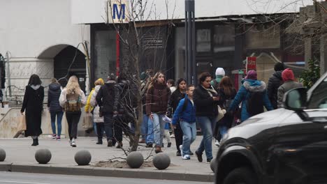 Busy-urban-street-scene-in-Bucharest-with-pedestrians-crossing-a-road,-shot-in-daylight