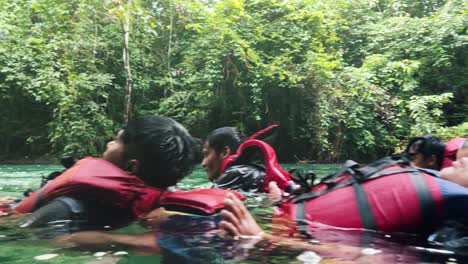 Closeup-of-people-wearing-life-jackets-and-floating-in-a-row-on-the-mountain-river