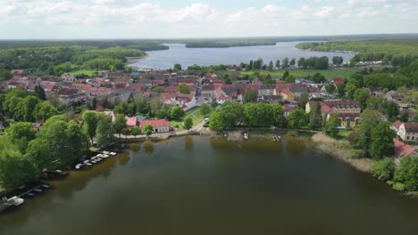 Eine-Malerische-Luftaufnahme-Einer-Charmanten-Stadt-Am-Ufer-Eines-Ruhigen-Sees