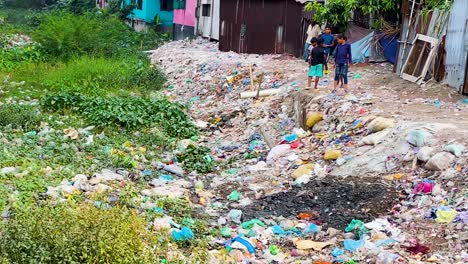 Niños-Cerca-De-Un-Vertedero-Sucio-Y-Contaminado-Cerca-De-Asentamientos-En-La-Ciudad-De-Dhaka,-Bangladesh