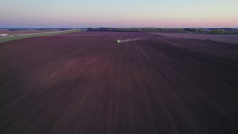 Luftaufnahme-Eines-Traktors,-Der-In-Der-Abenddämmerung-Ein-Feld-Pflügt