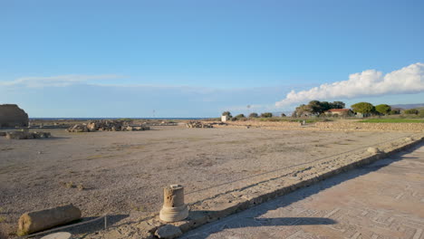 An-expansive-view-of-an-archaeological-site-in-Pafos,-with-ancient-ruins-and-stone-pathways-under-a-bright-blue-sky