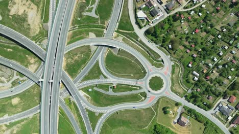 An-aerial-drone-zoom-in-shot-captures-intricate-highway-junction-with-cars-navigating-complex-roundabouts-and-intersecting-roads