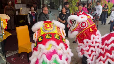 Pair-Of-Brightly-Coloured-Dragon-Performers-In-Costume-Dancing-In-Street-In-Los-Angeles-Outside-Business-During-Chinatown-Parade