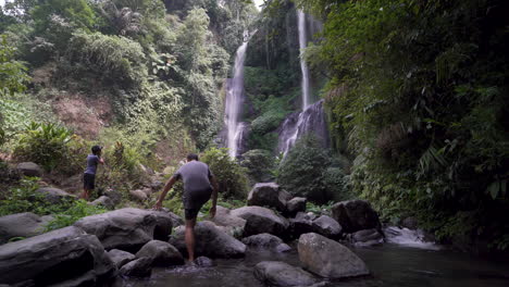 a-peron-walking-in-the-water-towards-a-beatiful-waterfall-in-Bali-indonesia-on-a-sunny-day