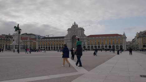 Tourists-visiting-famous-Arco-da-Rua-Augusta-with-statue-of-Dom-José-I-on-horse-under-a-cloudy-day-in-Lisbon,-Portugal