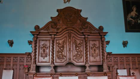 Exquisite-carved-wooden-buffet-with-ornamental-details-against-a-contrasting-blue-wall-in-Trakošćan-Castle,-Croatia