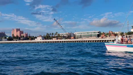 Party-boat-full-of-people-having-fun-near-Paradise-Island-in-The-Bahamas-with-Atlantis-hotel-view-in-the-horizon,-clear-water-sailing-4K-30-FPS