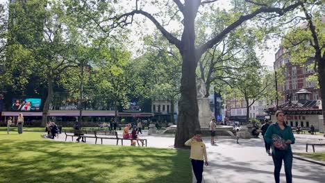 Profile-view-of-Leicester-Square-in-London-with-tourists-passing-in-England
