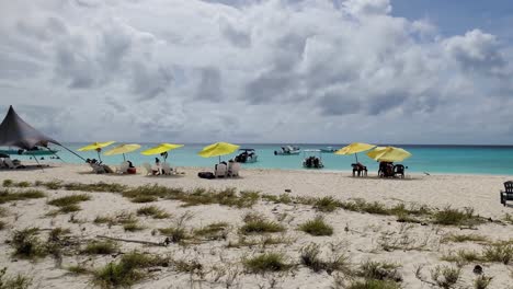 Cayo-de-agua-tropical-island-Los-Roques-with-tent-and-beach-umbrellas,-Pan-right