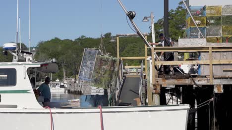 Commercial-lobster-fishermen-load-lobster-traps-onto-their-boat-from-the-dock-in-New-Harbor,-Maine