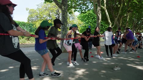 Slow-motion-shot-of-young-children-playing-tug-of-war-trying-to-win-and-smiling