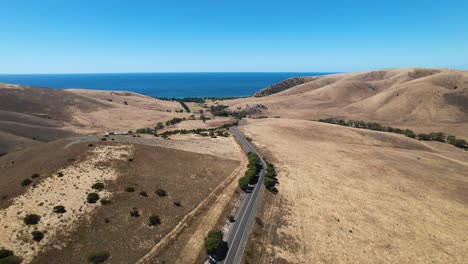 Drone-footage-over-a-long-road-which-cuts-through-some-stunning-scenery-in-the-fleurieu-peninsula,-South-Australia