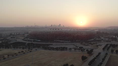 FNB-Stadium-Drone-Orbiting-Aerial-Shot-At-Sunrise-With-Johannesburg-CBD-In-The-Distance_01