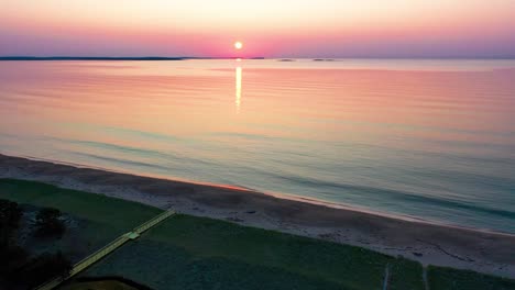 Luftaufnahme-Eines-Sonnenuntergangs-über-Strandhäusern-Mit-Farben,-Die-Sich-In-Den-Meereswellen-Widerspiegeln,-Und-Ferienhäusern-Entlang-Der-Atlantikküste-Von-Neuengland