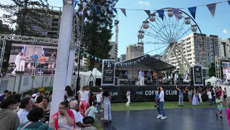 Children-playing-at-the-Paniyiri-Greek-festival-with-stage-and-Ferris-wheel-in-the-background