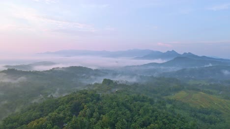 Luftaufnahme-Einer-Wunderschönen-Ländlichen-Landschaft-Mit-Blick-Auf-Landwirtschaftliche-Felder-Und-Hügel-Im-Nebligen-Morgen