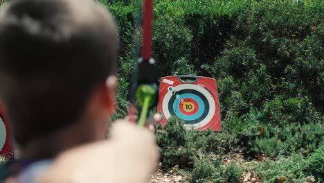 Cámara-Lenta-Sobre-El-Hombro-De-Un-Niño-Jugando-Tiro-Con-Arco-Y-Disparando-Flechas