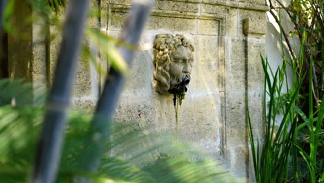 Slow-revealing-shot-of-a-greek-mythical-head-with-a-water-fountain-flowing
