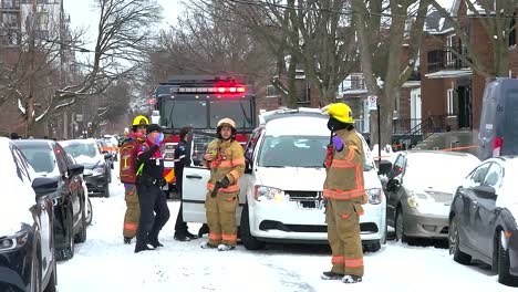 Fire-engine-and-firefighters-on-white-snowy-street-in-Quebec,-Canada