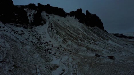 Icelandic-Mountains-with-Cliffs-Covered-in-Snow-with-an-Ascending-Drone-Over-the-Landscape-During-Evening-or-Early-Morning