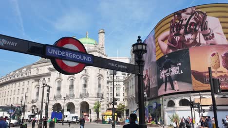 Piccadilly-Circus-Mit-Londoner-U-Bahn-Schild-Und-Geschäftiger-Menschenmenge-An-Einem-Sonnigen-Tag,-Mit-Prominenten-Digitalen-Werbetafeln