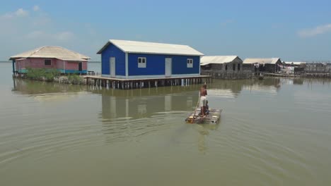 Two-kids-floating-in-a-raft-through-stilt-houses