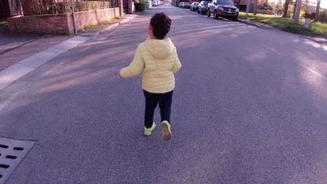 Little-toddler-girl-running-along-a-desert-street,-away-from-the-camera