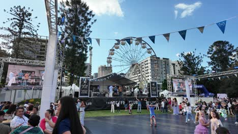 Children-playing-at-the-Paniyiri-Greek-festival-with-stage-and-Ferris-wheel-in-the-background