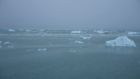 Sailing-by-Pieces-of-Ice-in-Cold-Ocean-Water-With-Misty-Horizon