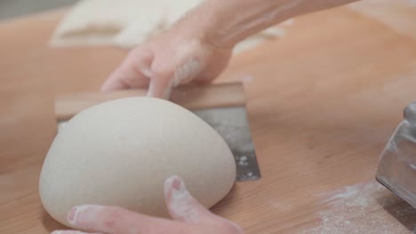 POV-of-baker-making-perfectly-round-bread-loaf-with-dough-scraper